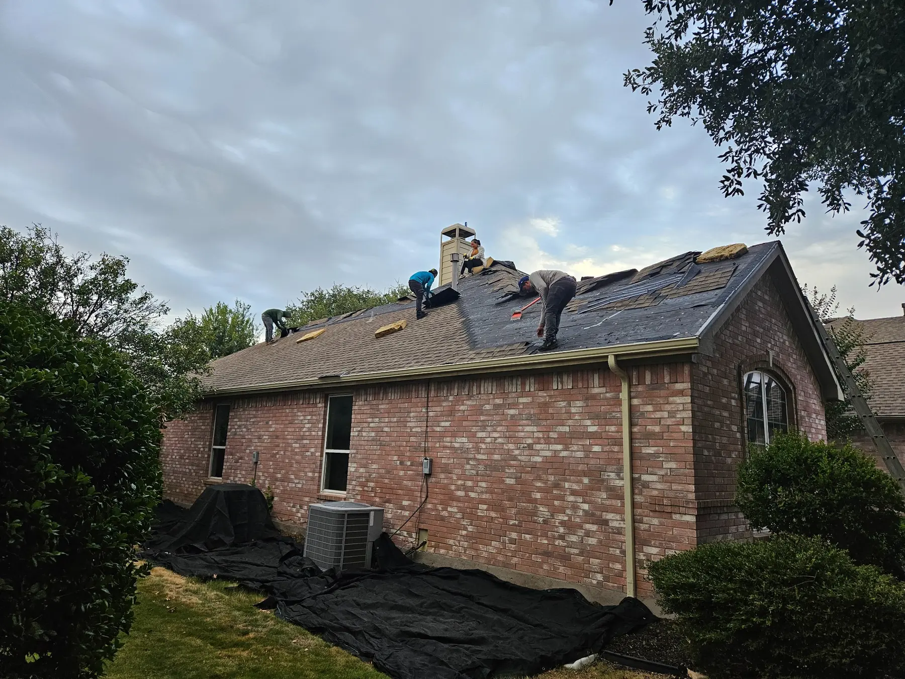 Roofing crew removing old shingles and preparing a residential roof
